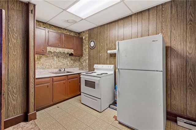 kitchen featuring a drop ceiling, wood walls, sink, white appliances, and a baseboard radiator