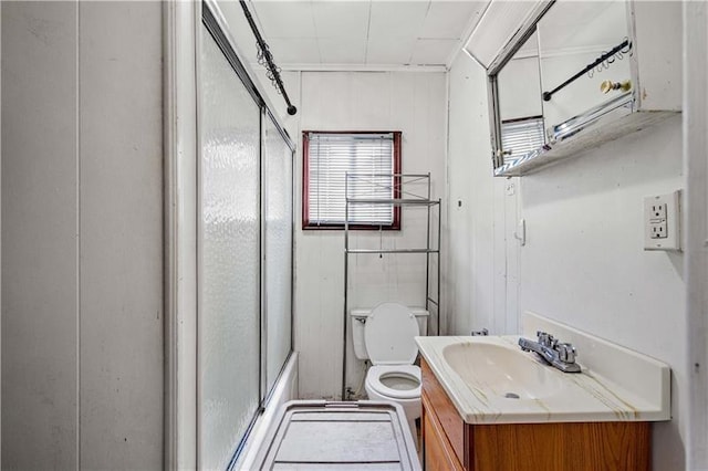 full bathroom featuring toilet, combined bath / shower with glass door, and vanity