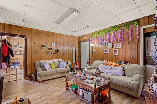 living room with a paneled ceiling, wooden walls, and wood-type flooring