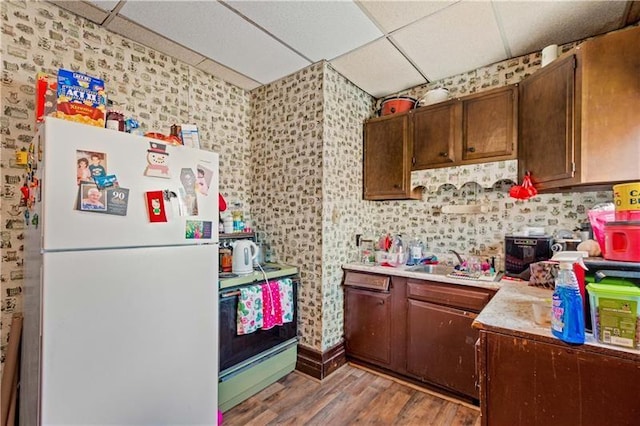 kitchen with a paneled ceiling, sink, light hardwood / wood-style floors, and white appliances