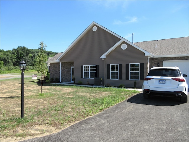 ranch-style house with central air condition unit and a front yard