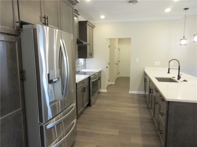 kitchen with dark hardwood / wood-style flooring, appliances with stainless steel finishes, decorative backsplash, pendant lighting, and sink