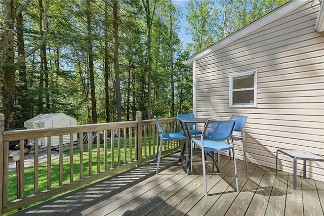 wooden terrace with a yard and a storage unit