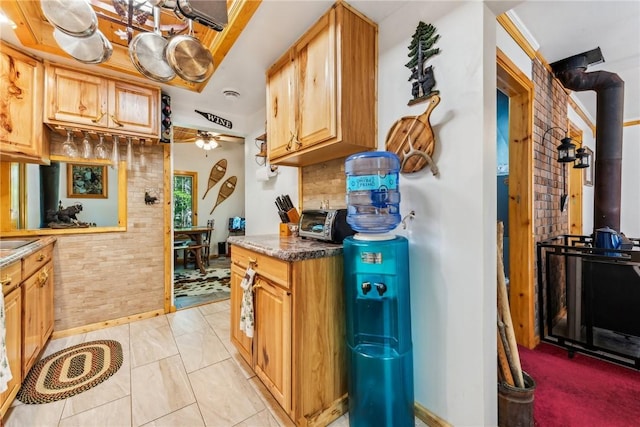 kitchen with ceiling fan, a wood stove, backsplash, and light tile patterned floors