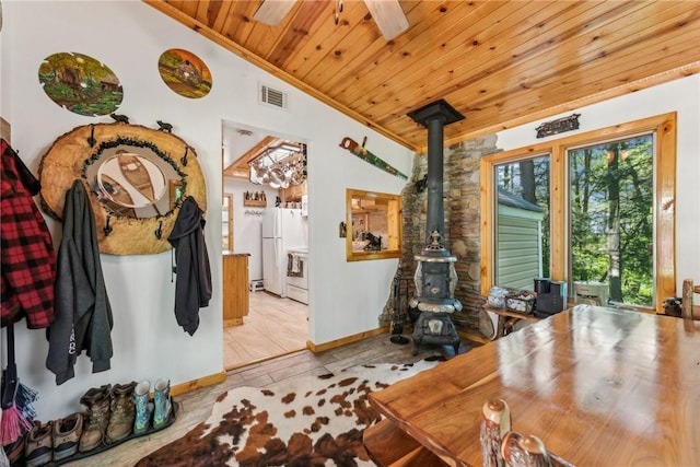 interior space featuring vaulted ceiling, ceiling fan, a wood stove, and wooden ceiling