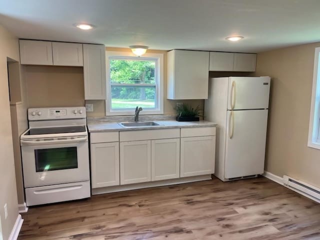 kitchen with white appliances, hardwood / wood-style floors, sink, white cabinetry, and baseboard heating