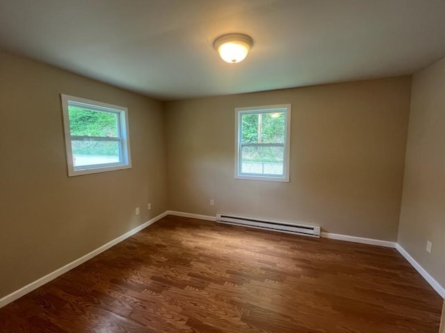 unfurnished room with a baseboard heating unit and hardwood / wood-style floors