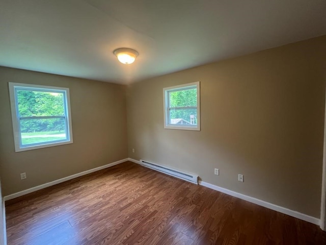 spare room with baseboard heating, a healthy amount of sunlight, and hardwood / wood-style floors