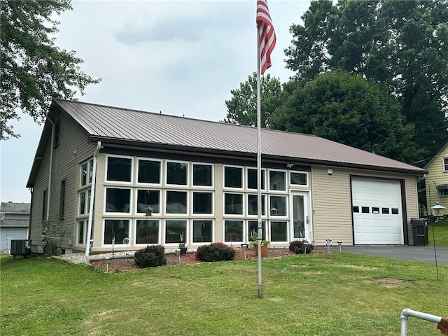 view of front of house featuring cooling unit, a garage, and a front yard