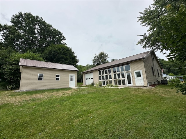 rear view of house with a garage, a yard, and an outbuilding