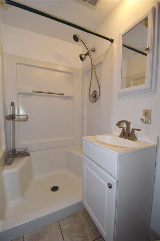 bathroom with tile patterned flooring, vanity, and a shower