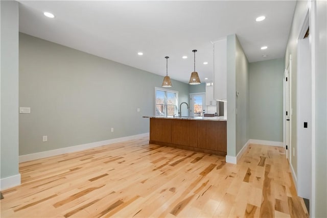 bar featuring hanging light fixtures, sink, and light hardwood / wood-style floors