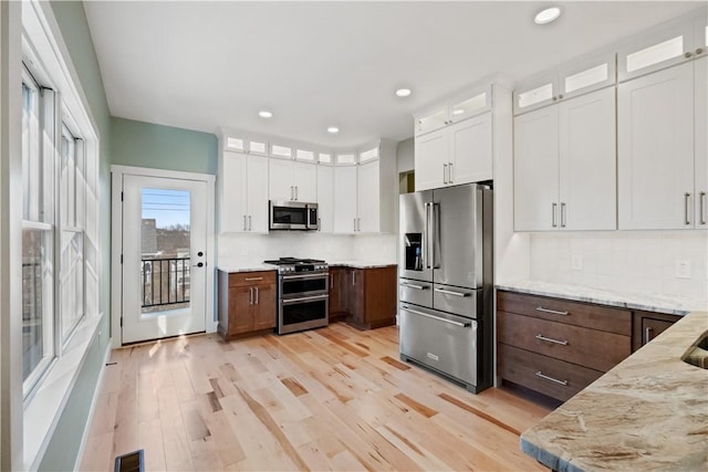 kitchen featuring light stone countertops, white cabinetry, stainless steel appliances, and dark brown cabinets