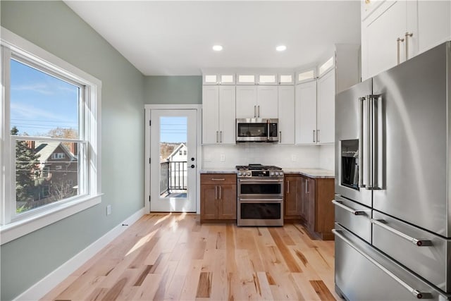 kitchen featuring light stone counters, plenty of natural light, white cabinets, and stainless steel appliances