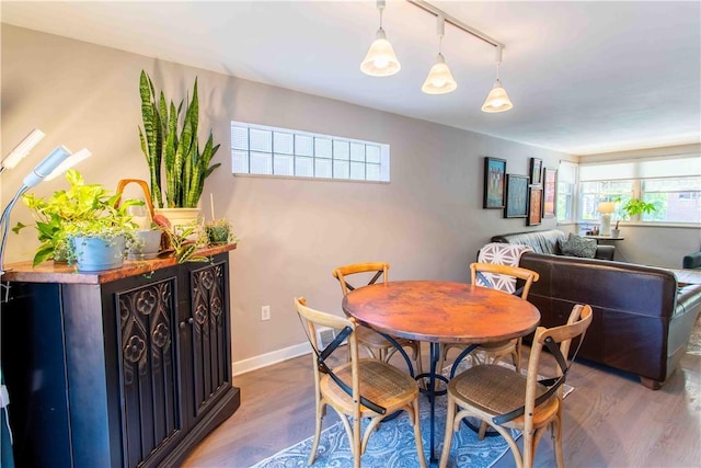 dining space with rail lighting and hardwood / wood-style floors