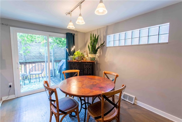 dining area featuring track lighting, wood-type flooring, and a healthy amount of sunlight