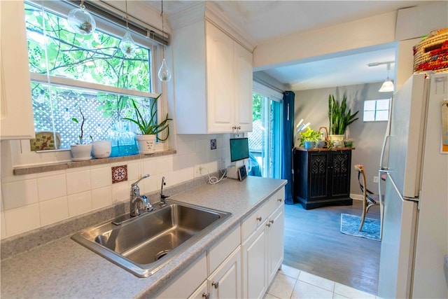 kitchen featuring white refrigerator, sink, backsplash, light hardwood / wood-style floors, and decorative light fixtures