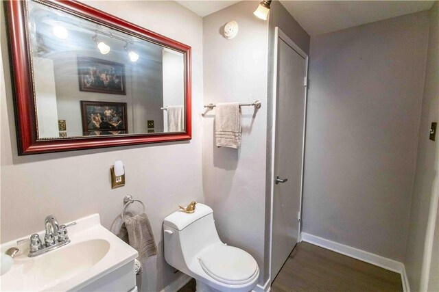 bathroom with hardwood / wood-style flooring, toilet, and vanity