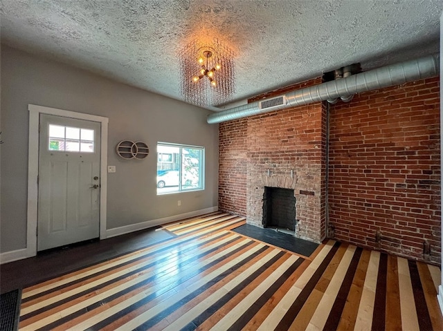 unfurnished living room featuring brick wall, a chandelier, hardwood / wood-style flooring, and a healthy amount of sunlight