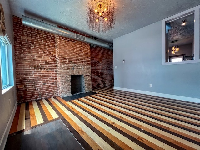 unfurnished living room featuring a fireplace, wood-type flooring, a wealth of natural light, and a chandelier