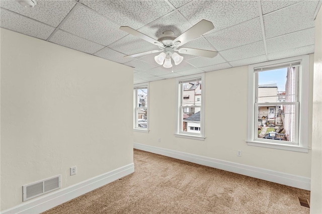 unfurnished room featuring a paneled ceiling, carpet, and ceiling fan