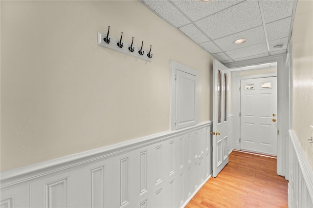 hallway with light wood-type flooring and a paneled ceiling