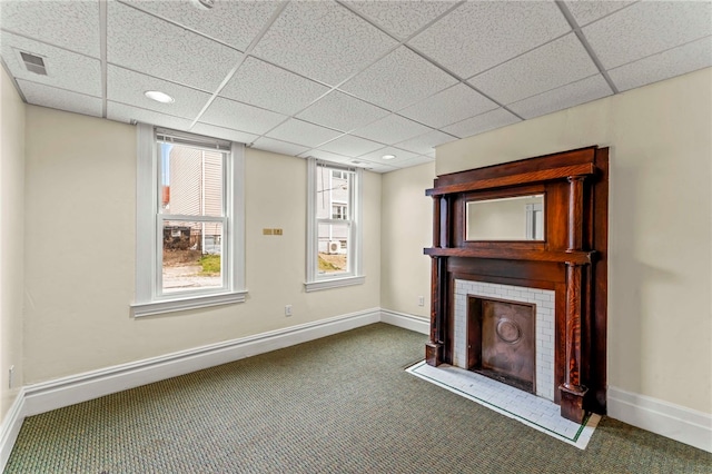 unfurnished living room with dark colored carpet, a fireplace, and a paneled ceiling