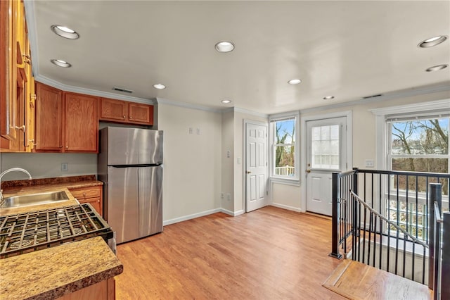 kitchen featuring sink, light wood-type flooring, stainless steel refrigerator, and ornamental molding