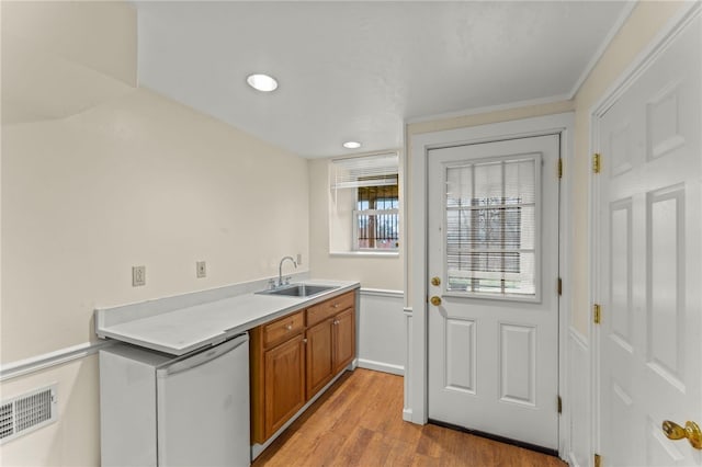 kitchen featuring dishwasher, light hardwood / wood-style flooring, sink, and ornamental molding