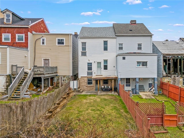 back of property featuring a wooden deck, a lawn, and a patio area