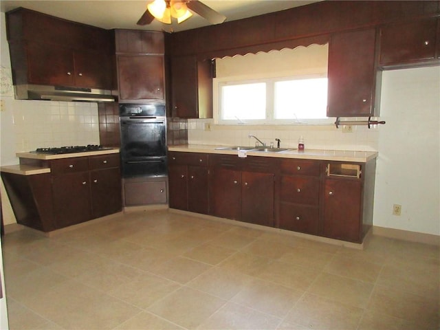 kitchen featuring backsplash, ceiling fan, sink, exhaust hood, and black oven