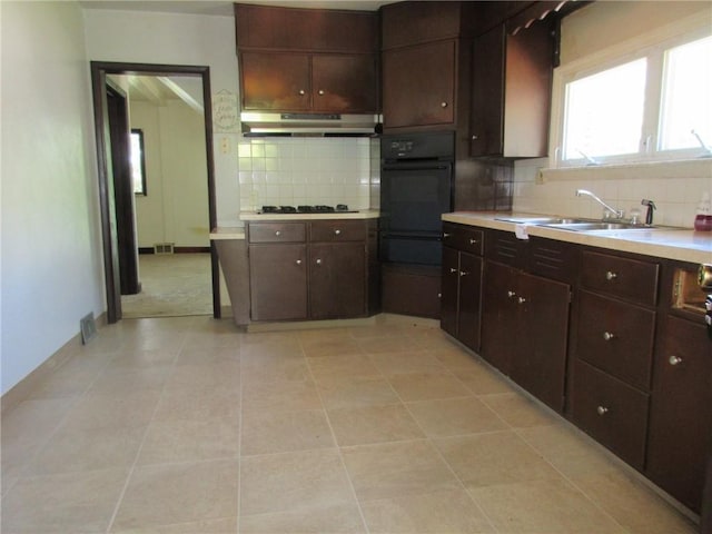 kitchen with dark brown cabinetry, tasteful backsplash, black oven, and sink