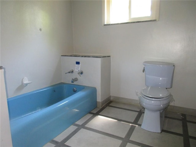 bathroom featuring tile patterned flooring, a washtub, and toilet