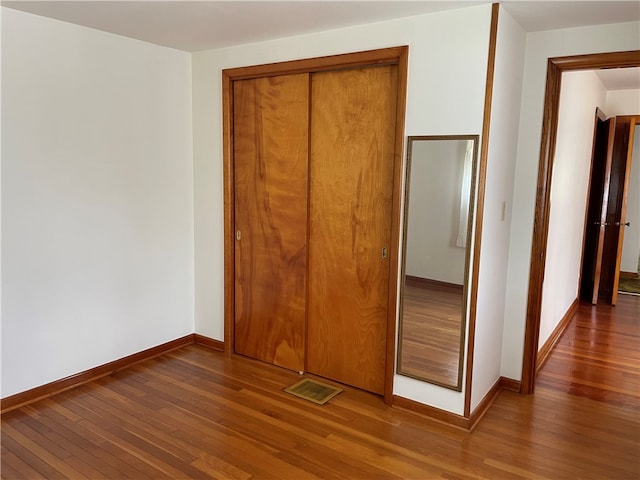 unfurnished bedroom with dark hardwood / wood-style floors and a closet