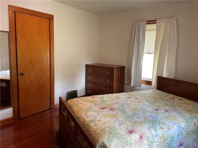 bedroom with dark hardwood / wood-style flooring and a closet