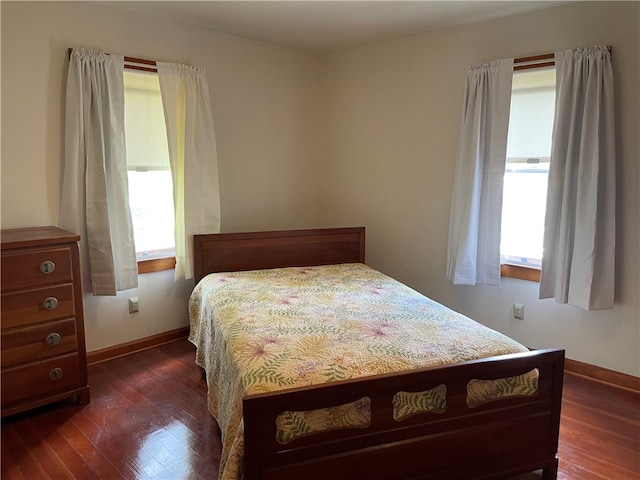 bedroom with dark hardwood / wood-style floors and multiple windows