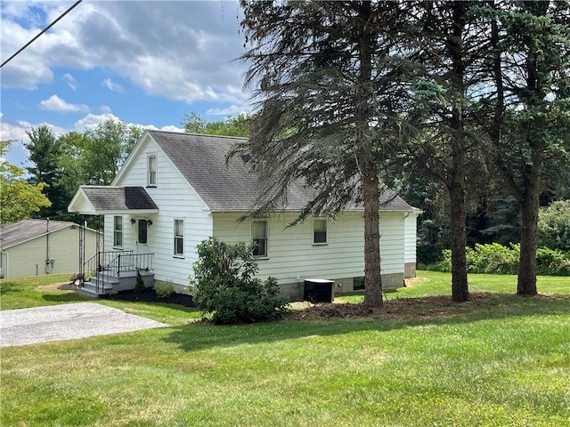 rear view of property with central AC unit and a yard