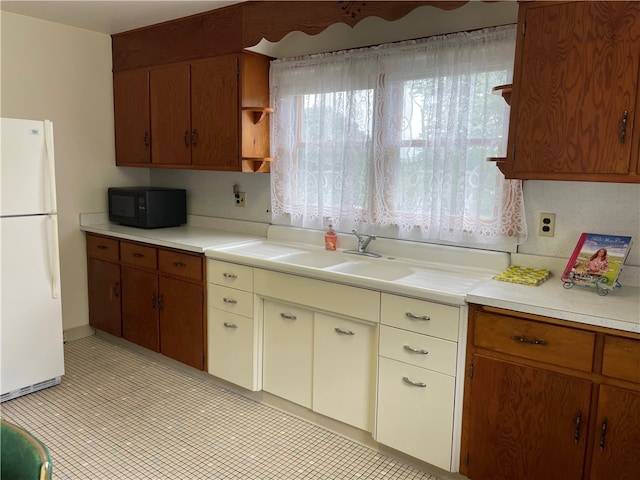 kitchen featuring white fridge, sink, and light tile patterned floors