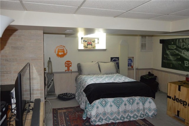 bedroom featuring a paneled ceiling and wood walls