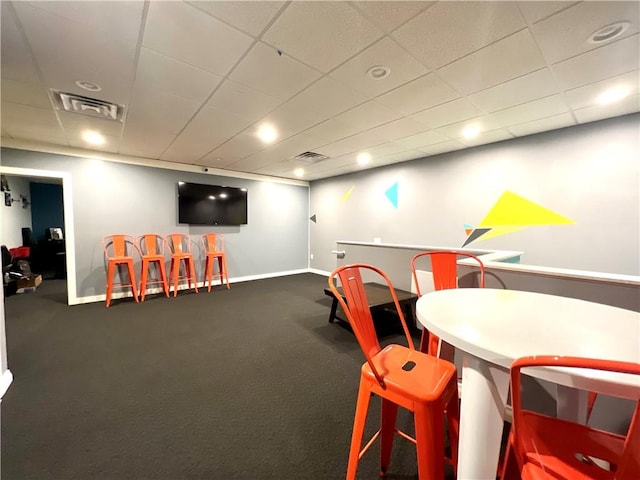 recreation room with a drop ceiling and dark colored carpet