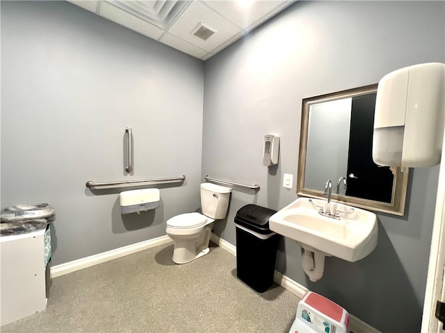 bathroom with a paneled ceiling, toilet, and sink