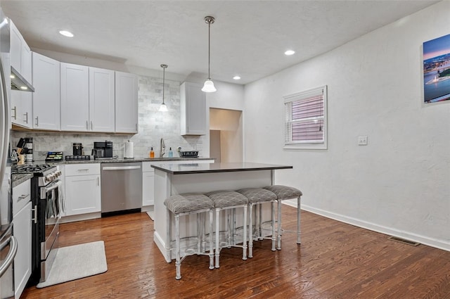 kitchen featuring a breakfast bar, a sink, tasteful backsplash, wood finished floors, and stainless steel appliances