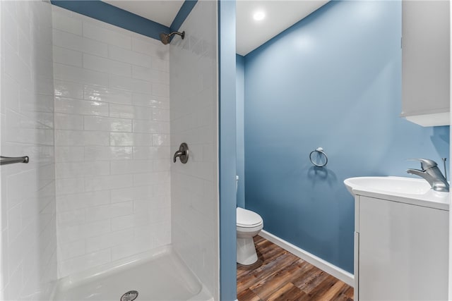 bathroom with vanity, a tile shower, wood-type flooring, and toilet