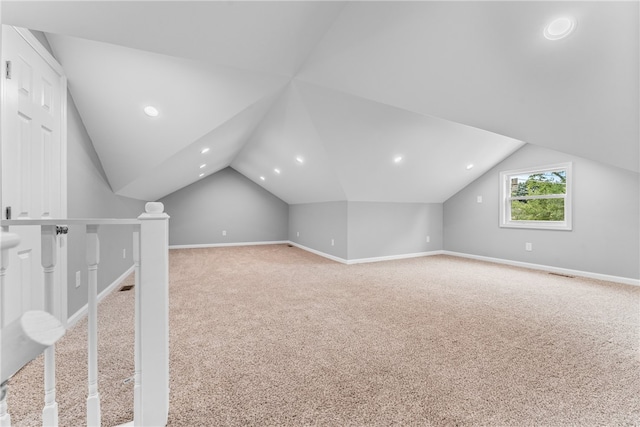 bonus room with lofted ceiling and light carpet