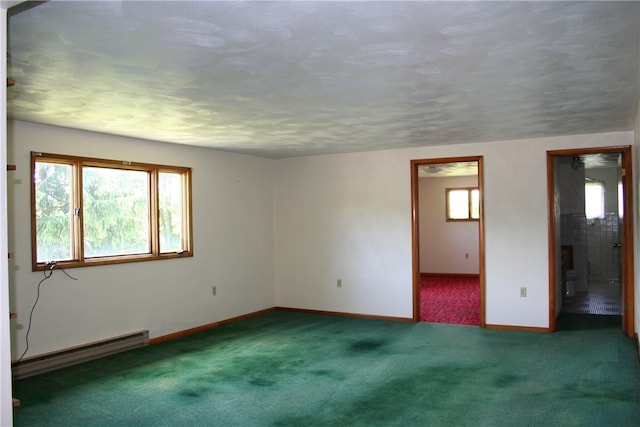 carpeted empty room featuring a baseboard heating unit, baseboards, and a textured ceiling