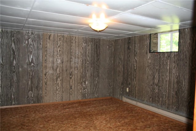 unfurnished room featuring baseboard heating and wooden walls