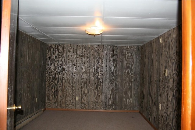 unfurnished room with a baseboard heating unit and wood walls