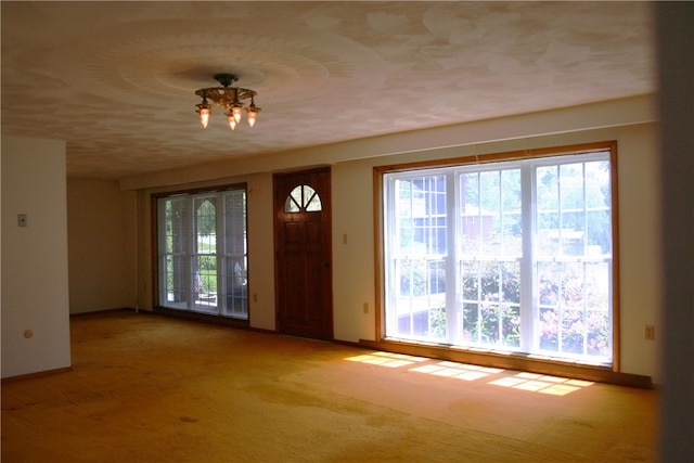 carpeted entryway with a notable chandelier