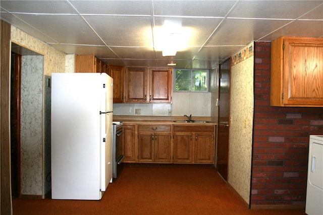 kitchen with dark carpet, stainless steel range with electric stovetop, sink, white refrigerator, and washer / dryer