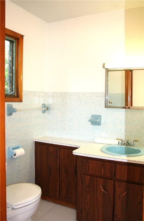 bathroom featuring toilet, vanity, tile patterned floors, and tile walls